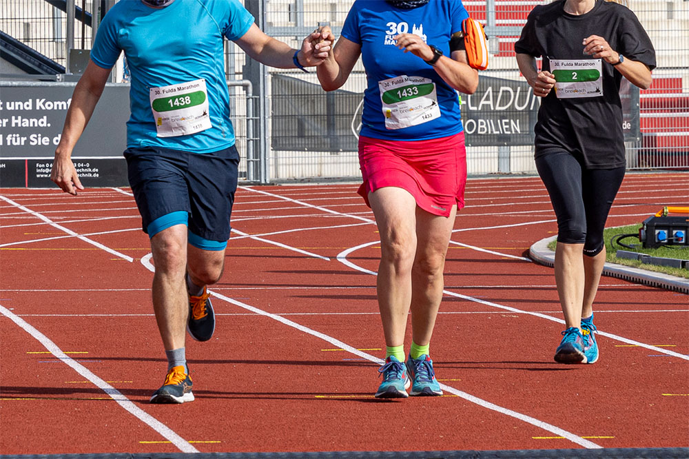 Zwei Läufer laufen gemeinsam durchs Ziel des Fulda Marathon
